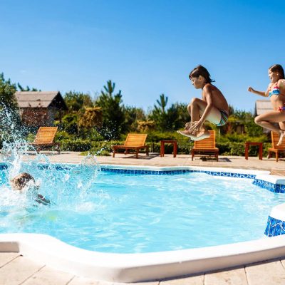 Cheerful children rejoicing, jumping, swimming in pool. Copy space